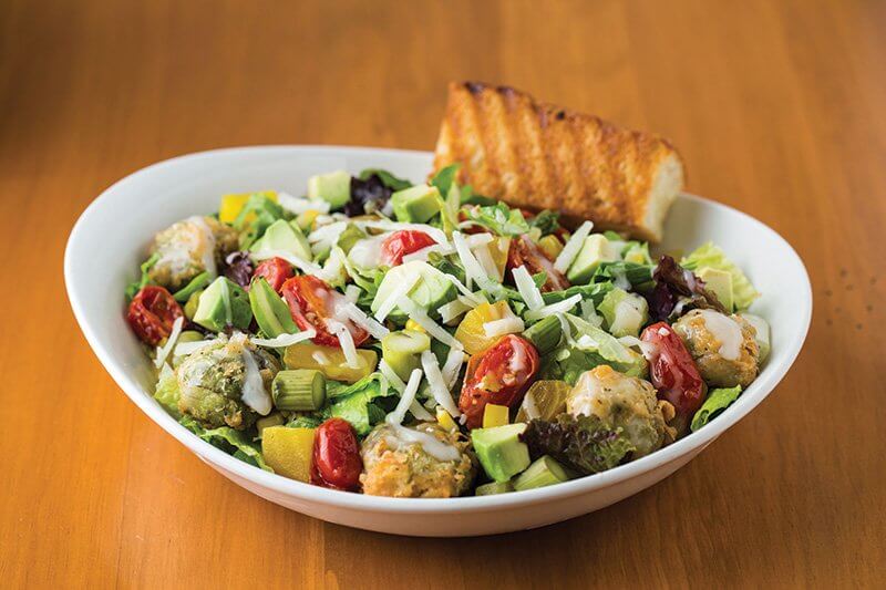 The Harvest Salad at TR Fire Grill is a study in thoughtfully constructed flavor and texture play—from the batter-dipped Brussels sprouts and smoked asparagus to the roasted tomatoes and golden beets.
