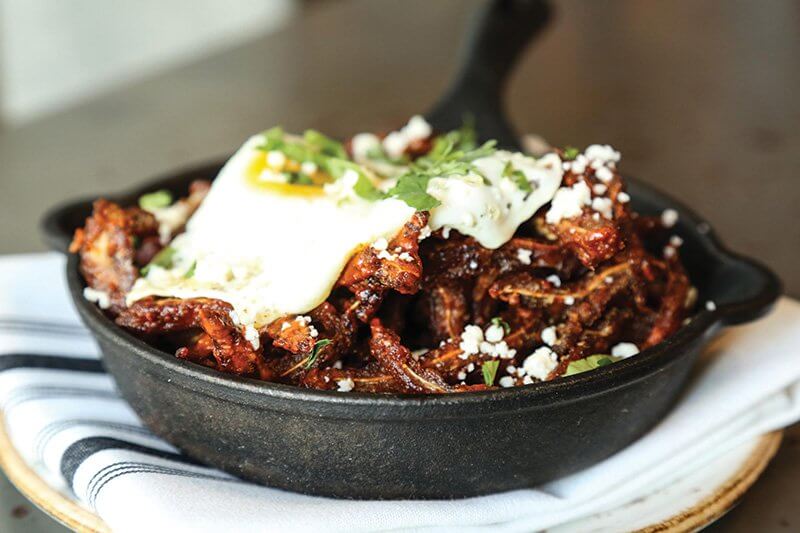 The depth and heat of chile colorado sauce enlivens dishes like the Crispy Pig Ear Chilaquiles at Johnny Sánchez in New Orleans.