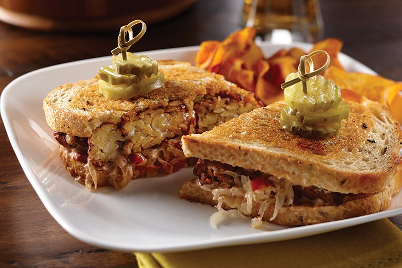 Tempeh subs for corned beef in this vegan version of the Reuben. Sauerkraut, tangy dressing and rye bread maintain the recognizable flavor profile.