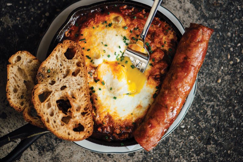 Farm Eggs in Purgatory, with andouille sausage and jalapeño tomato braise, balances savory and spicy at Toups South in New Orleans. Toasted ciabatta lends itself to dunking.