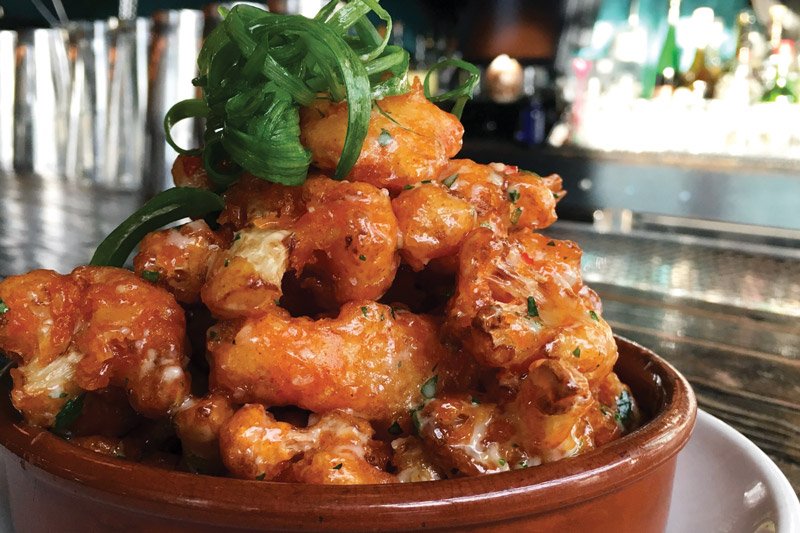 Cauliflower florets at La Sirena Clandestina are lightly battered in a gluten-free flour blend, then fried, sprinkled with parsley, and served with spicy lemon mayo.