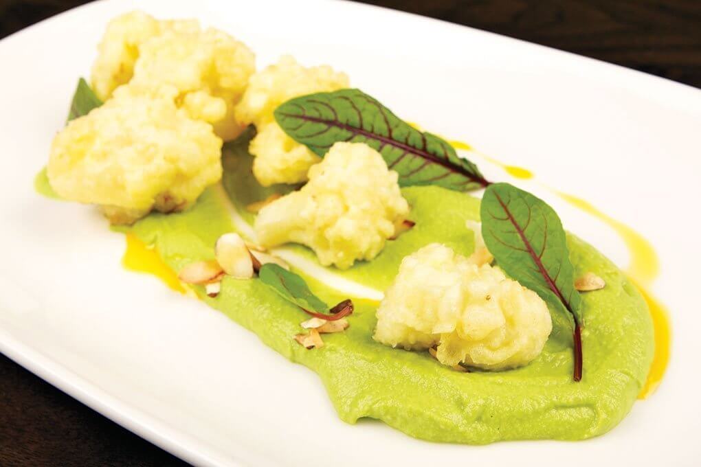 A smoked pea hummus forms a contrasting base for crispy cauliflower in the small plate offering at E+O Food and Drink in Elmhurst, Ill.