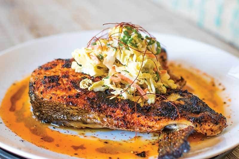 Chef Arthur Gonzalez features catch-of-the-day fish collar on the menu at Roe Seafood in Long Beach, Calif., seasoning it with a proprietary seven-spice blend and topping it with a sesame slaw.