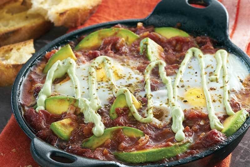 Avocados, along with a drizzle of cooling avocado crema, add a modern twist to the classic Middle Eastern shakshuka.