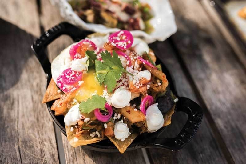 Chilaquiles at Habitat in Miami Beach, Fla., smoothly blends different global influences, featuring black bean purée, charred tomatillo salsa verde, Korean pulled pork, tortilla chips, a fried egg and kimchi.