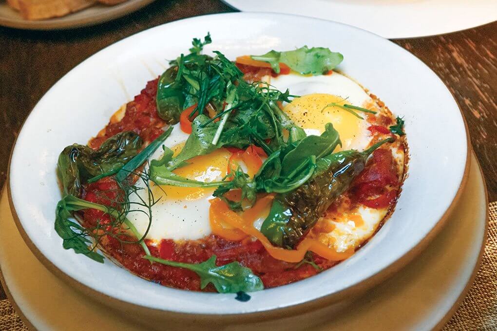 New York’s Temple Court menus Baked Eggs with stewed fresh tomatoes and roasted peppers, finished with fresh herbs.