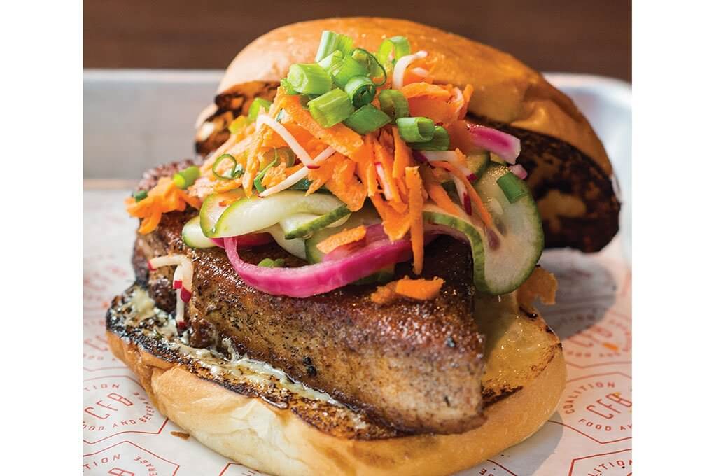 Blackened Tuna Burger with wasabi-ginger aïoli, marinated cucumber, onion, radish, carrots on a milk bun