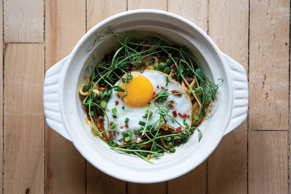 Kimchi Carbonara: udon, kimchi cream, Spam crumbs, green onions, sunny-side-up egg, pea tendrils 