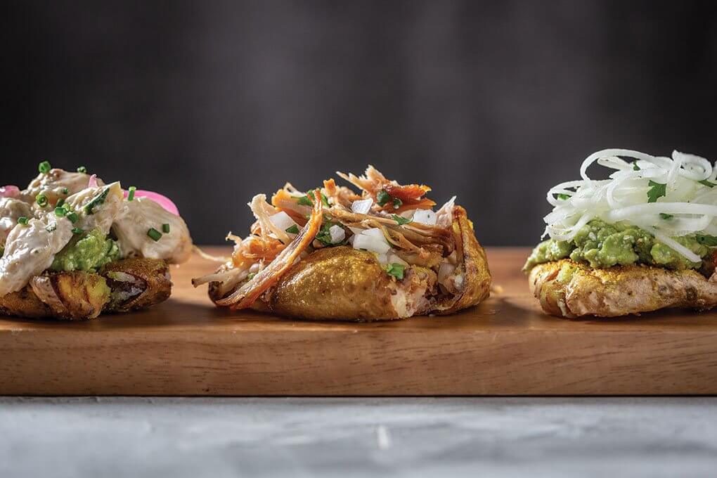 Crispy smashed baby potatoes with blue crab salad, carnitas and guacamole