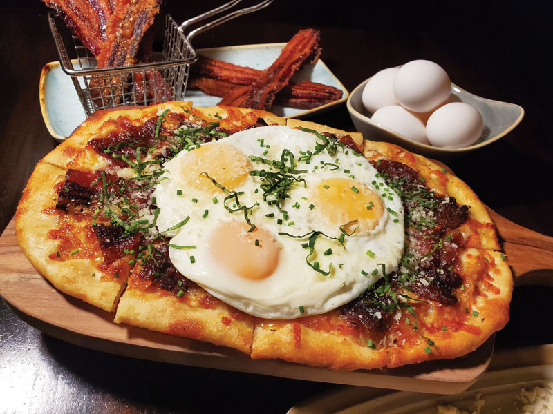 Village Tavern leaned into comfort-centric menu development with its new Breakfast Pizza, featuring sugared bacon, caramelized onions, Parmesan and a fried egg.