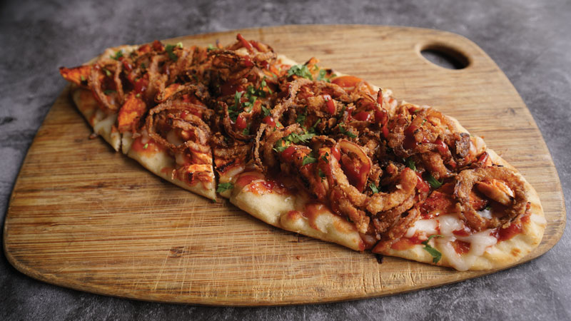 O.C. Breads & Bowls, a new virtual kitchen operating out of Daily Grill’s back of house, serves delivery items only, like this BBQ Chicken Flatbread with fontina, barbecue chicken breast and crispy fried onions.