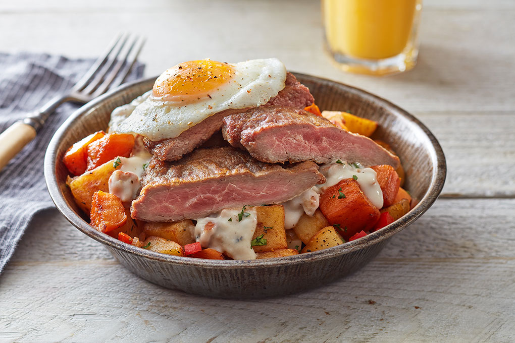 Chicken-fried Aussie steak crowns a comforting breakfast bowl of potato hash and sausage gravy.