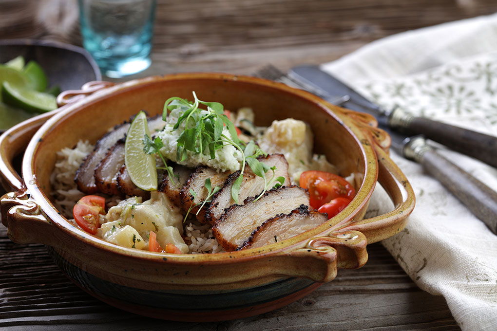 This Pork Belly Over Chickpea Stew and Rice is paired with coconut chutney and potato curry. Undertones of cardamom, lemon and Serrano build deep flavor.