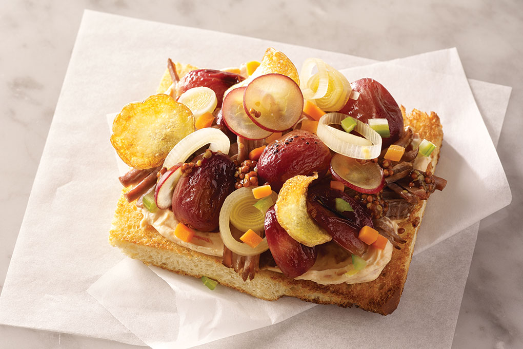 A base spread of pimento cheese adds a signature, craveable touch to chef Adam Moore’s toast build of Wagyu brisket and smoked grapes.