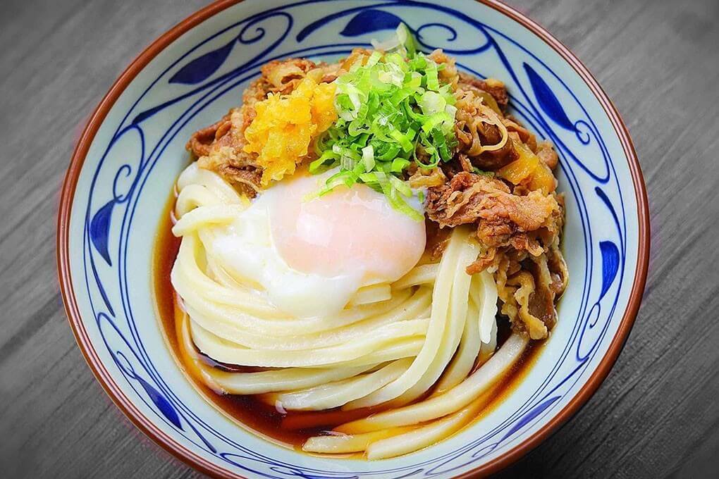 Curry Nikutama Udon with Japanese curries, beef, caramelized onions, a soft- poached egg, tempura flakes and green onions