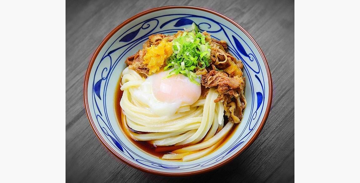 Curry Nikutama Udon with Japanese curries, beef, caramelized onions, a soft- poached egg, tempura flakes and green onions