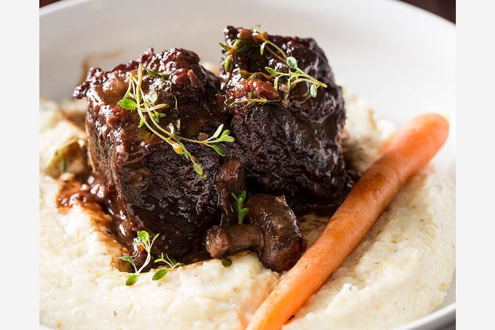 Spice-Rubbed Korean Short Ribs with smoked Gouda grits, roasted carrot, mushrooms and micro greens