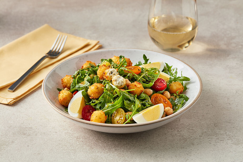This salad features a variety of textures and flavors, layering fried cheese cubes over peppery arugula, sweet cherry tomatoes, chickpeas, creamy hard-boiled eggs and a sweet and sour vinaigrette.