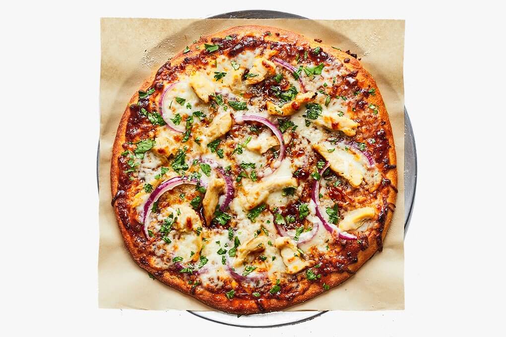 BBQ Chicken-Bacon-Ranch Pizza with barbecue sauce and mozzarella cheese, topped with chicken, bacon, cilantro, red onions and a swirl of housemade ranch dressing