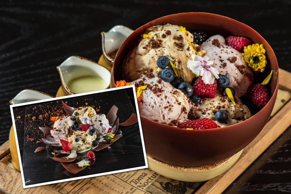 Strawberry ice cream and cream cheese mousse with fresh berries and almond cookie crumbles in an edible chocolate bowl, with tableside sauces