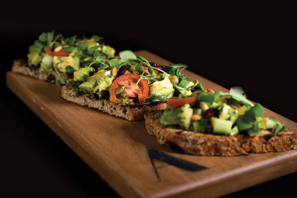 Michael Shaughnessy, executive chef/owner of Advellum, the “vegetable eatery” at Malcolm Yards in Minneapolis, menus a creative take on avocado toast topped with cucumbers, baby tomatoes, radish, lime, arugula, pepitas and charred tomatillo vinaigrette on grilled cranberry wheat.
