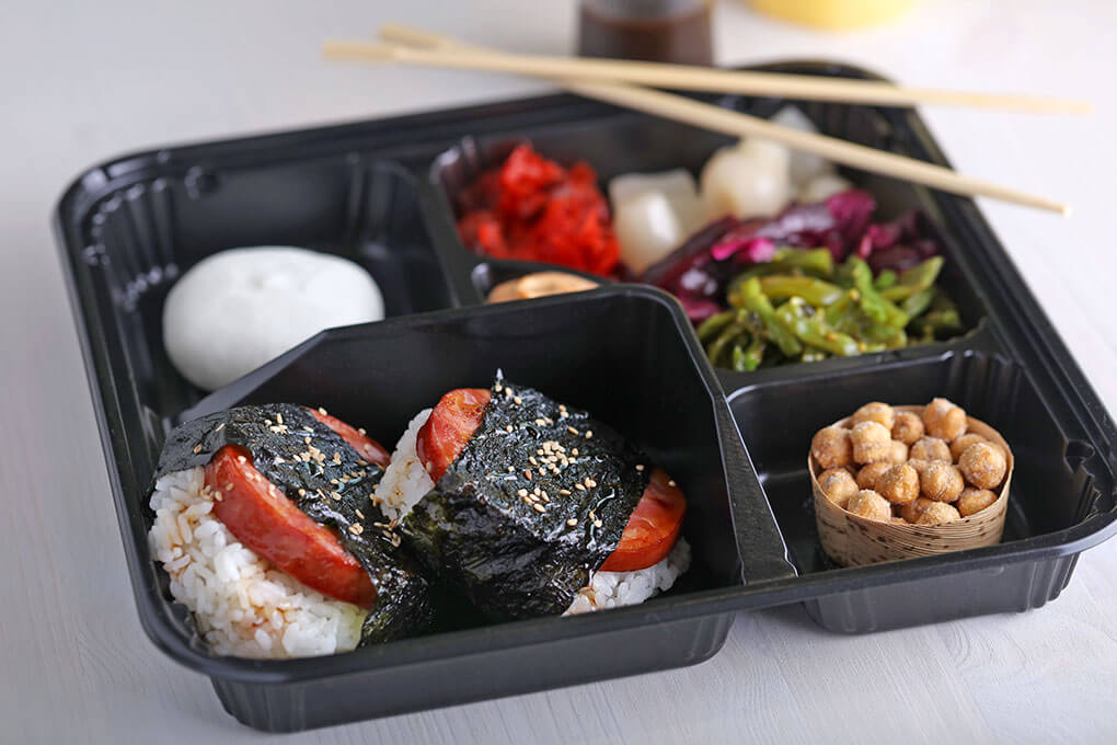 This Maple-Glazed Smoked Canadian Bacon Musubi Bento combines the smoky-sweet flavors of the protein with roasted seaweed and togarashi for a double hit of umami and briny complexity.