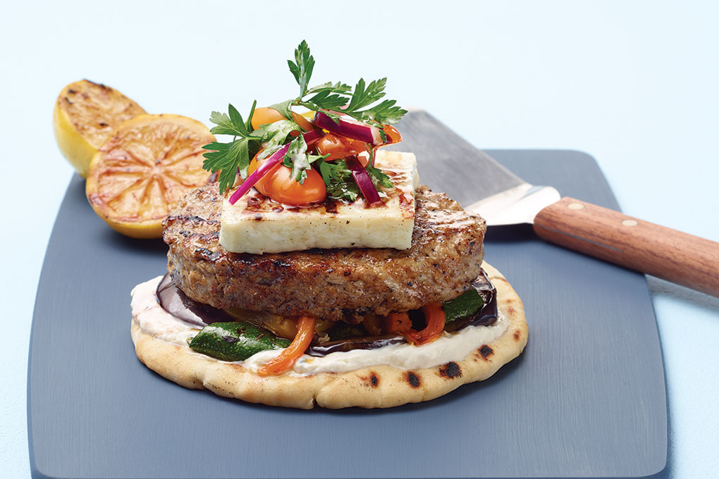 This Mediterranean Turkey Burger is juicy and flavorful, set over grilled pita slathered with tzatziki and roasted peppers, then topped with grilled halloumi cheese and a bright parsley salad.