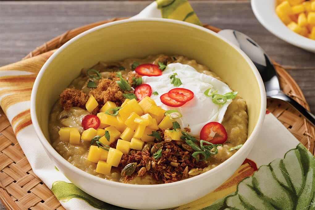 Fresh Mango Oatmeal Congee is topped with granola, pork sung and a poached egg to create a unique, savory breakfast bowl.