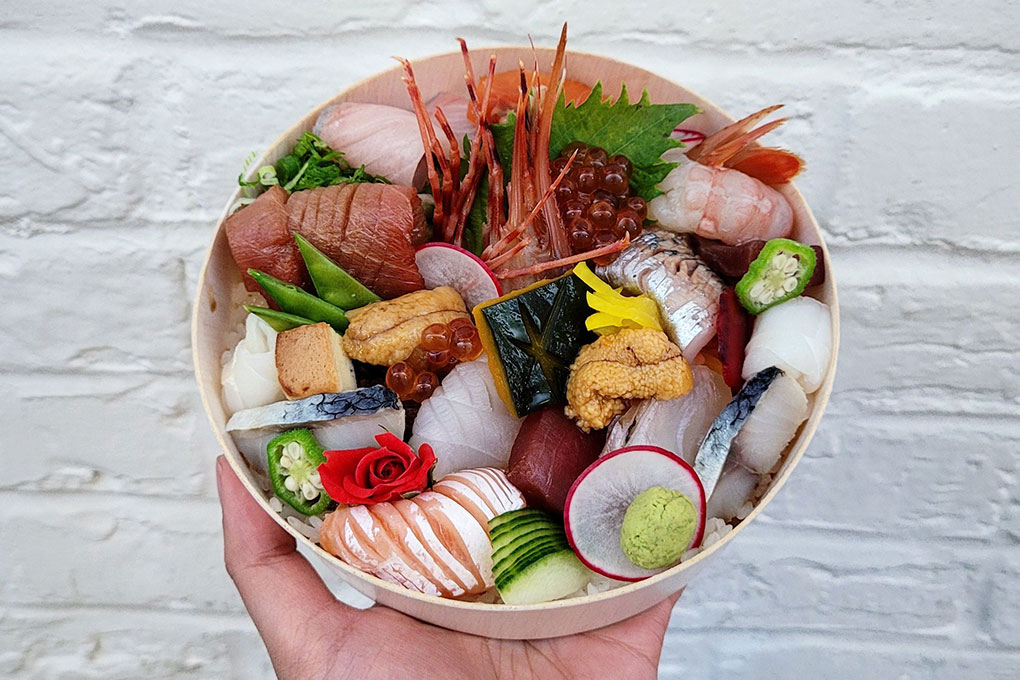Vibrant and versatile chirashi bowls showcase several types of seafood, often accented by fresh or pickled produce items and a dollop of wasabi. Ama Ami in Washington, D.C., features to-go chirashi bowls as an extension of its sushi offerings.