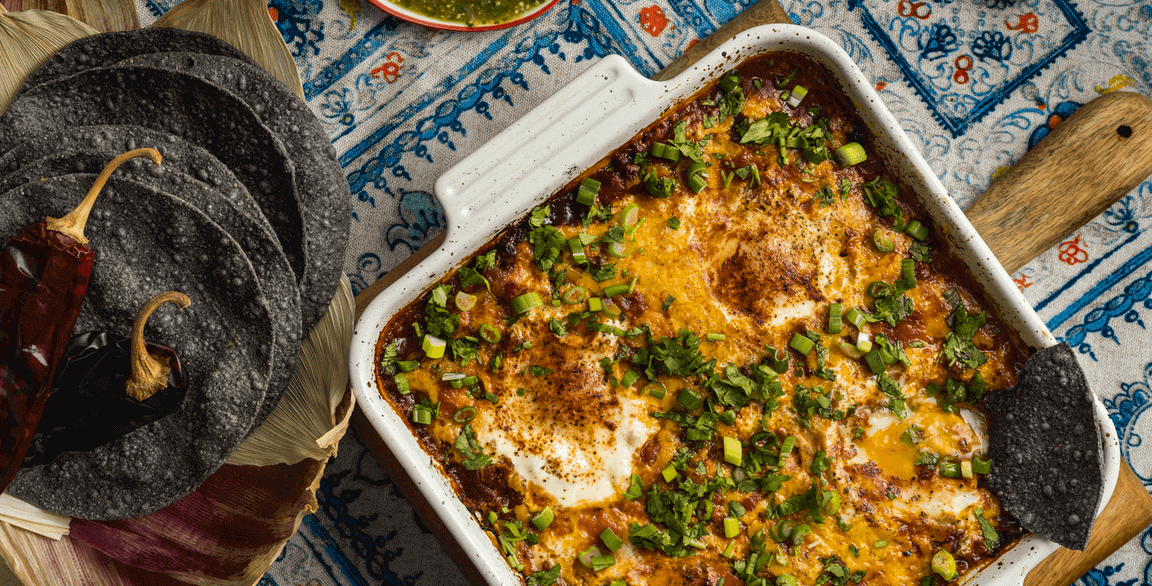 A savory bake inspired by huevos rancheros builds on a foundation of crispy tortillas, adding fried eggs and salsa verde, chile dust, a charred cheese crust, scallions and cilantro.