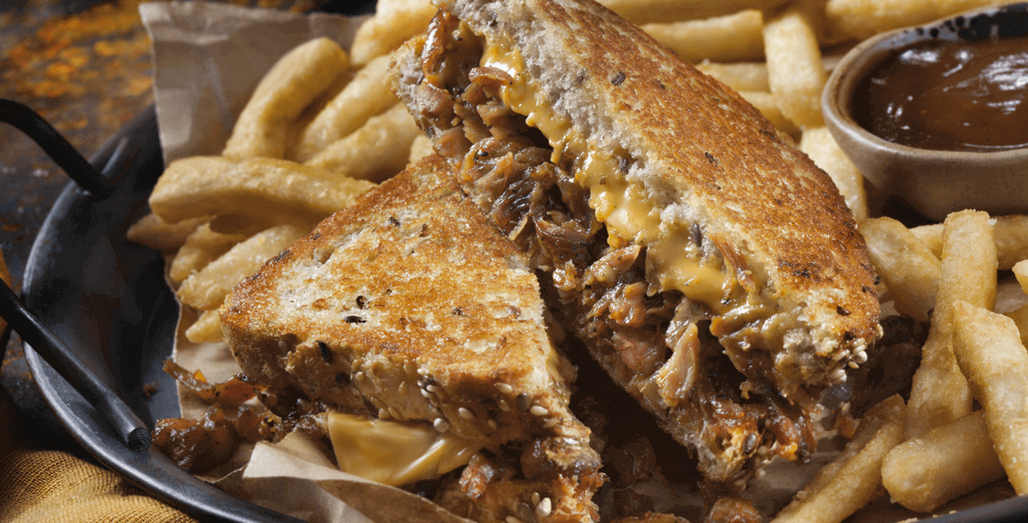 Achiote-spiced pulled pork moves this classic grilled cheese into a flavor-packed signature sandwich. Achiote-spiced pulled pork moves this classic grilled cheese into a flavor-packed signature sandwich.