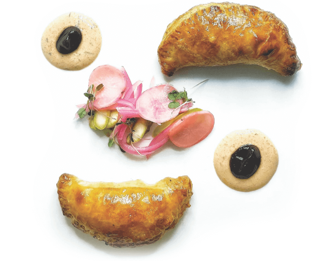 A premium protein swap elevates the humble empanada at Royal Oaks Country Club in Houston. The upscale Lamb Empanada, featuring spiced Australian ground lamb, is plated with tamarind sauce, harissa yogurt sauce and pickled vegetables.