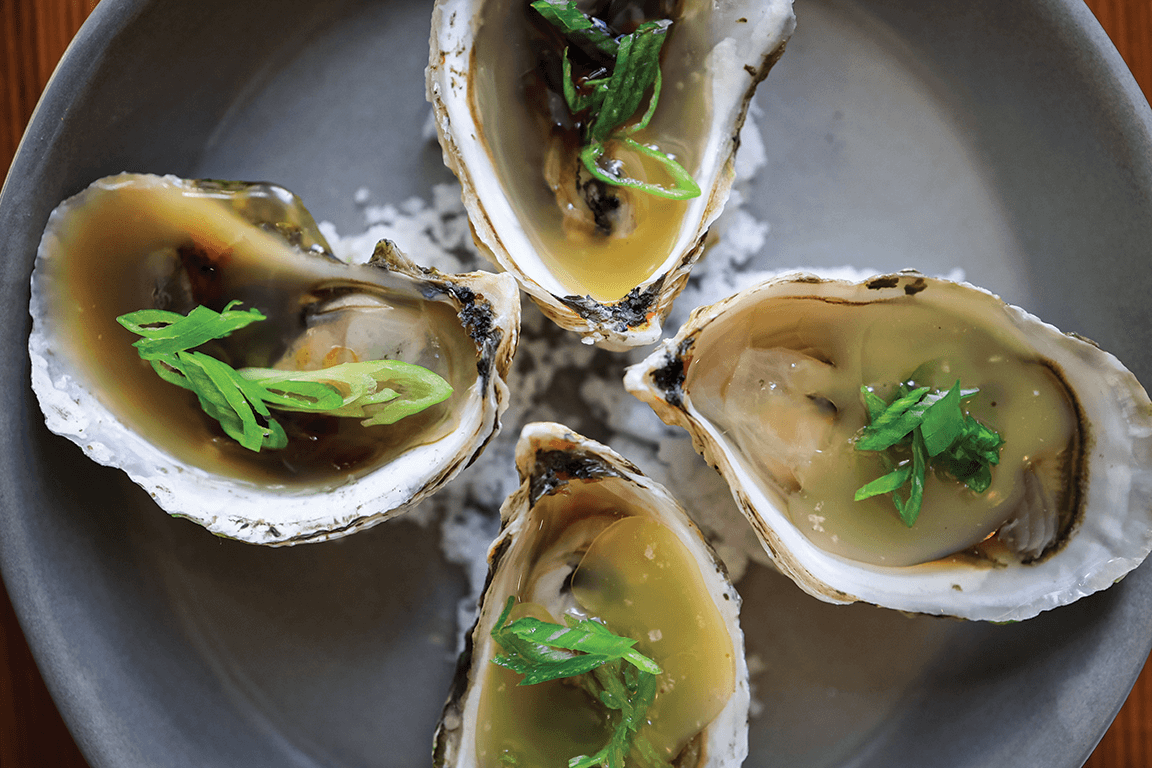 Grilled Oysters sit in a lush puddle of brown butter at The Kitchen American Bistro, with locations in Chicago, Denver and Boulder, Colo.